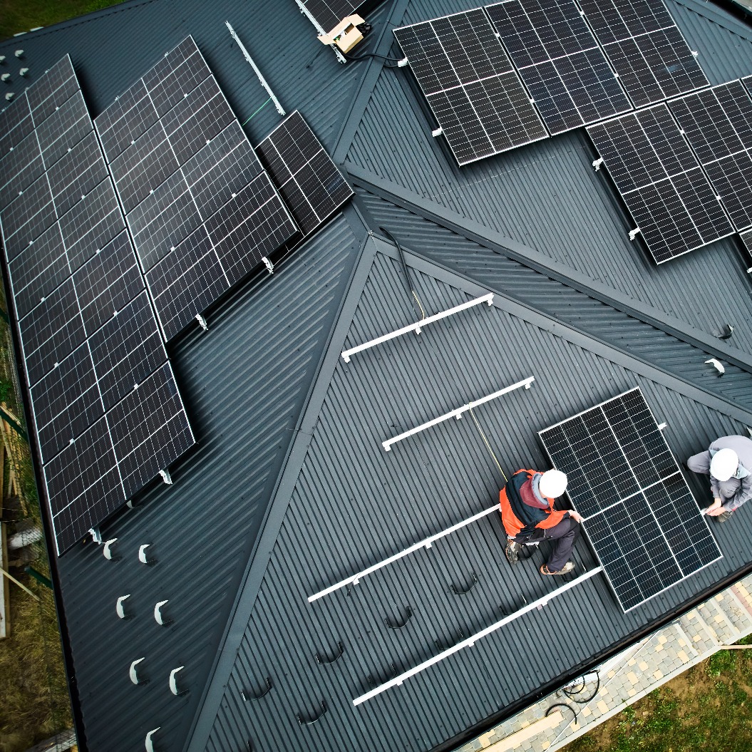 Männer installieren Sonnenkollektoren auf dem Dach eines Hauses.